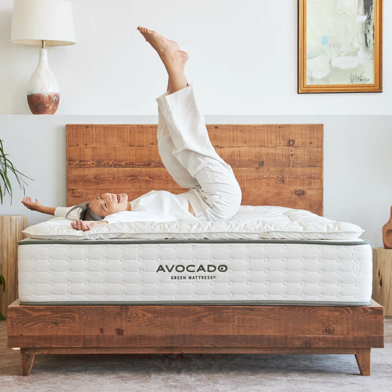 Woman happily laying on a Wool Mattress Topper from Avocado