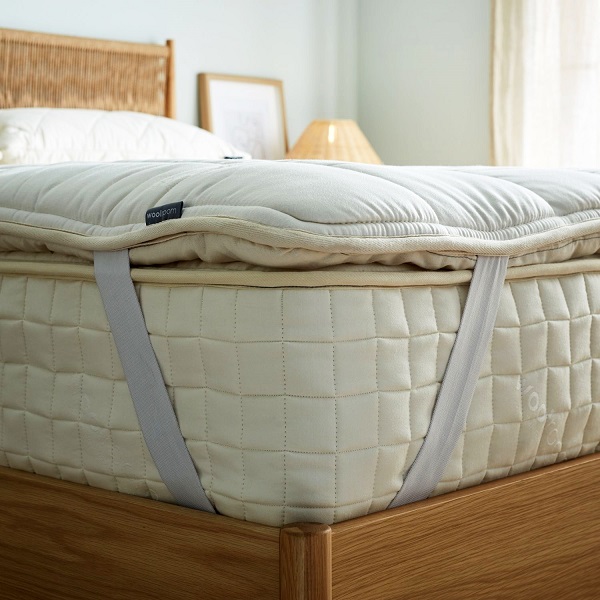 Woolroom Wooly Mattress Topper secured to a thick mattress with straps