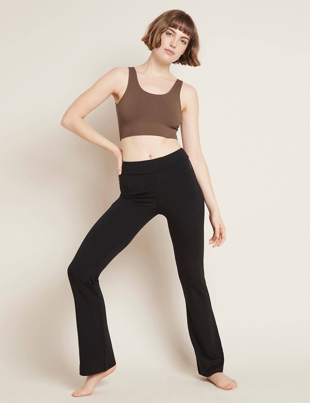 A woman wearing a brown sports bra and black flared bamboo leggings from Boody