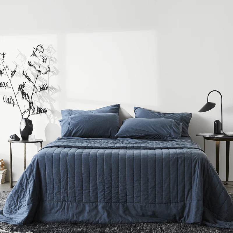 Ettitude hemp linen quilt in blue spread across a bed