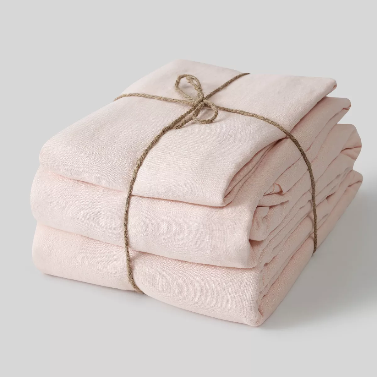 Two linen pillowcases, a fitted linen sheet, and a flat linen sheet tied together with rope