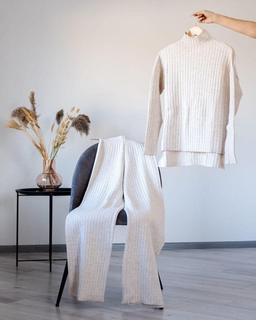 A pair of pants draped over a chair and a matching top held to the side