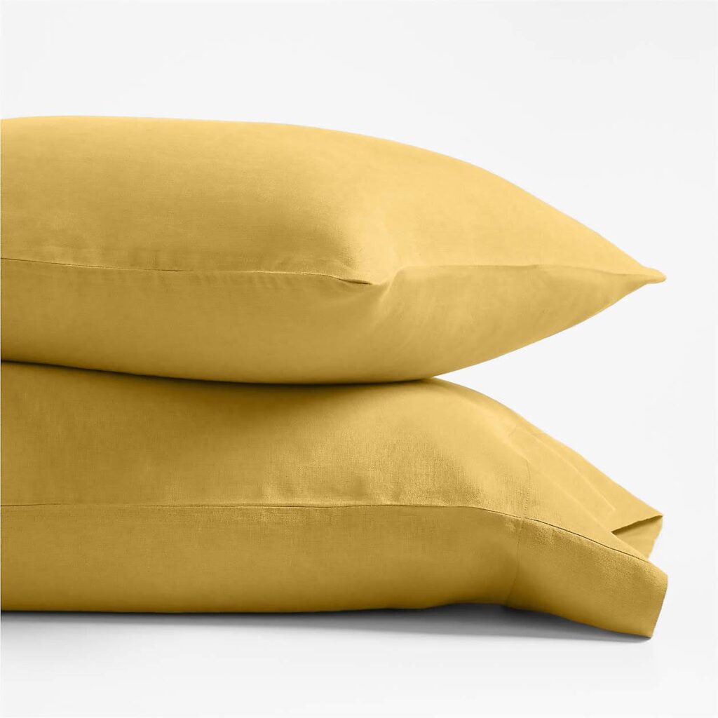 Two pillows covered in yellow pillow cases stacked on top of each other