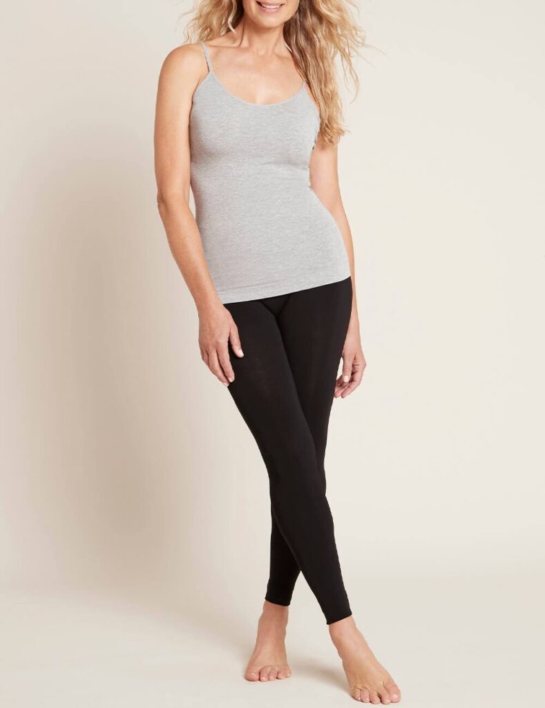 A woman wearing a gray tank top and black leggings