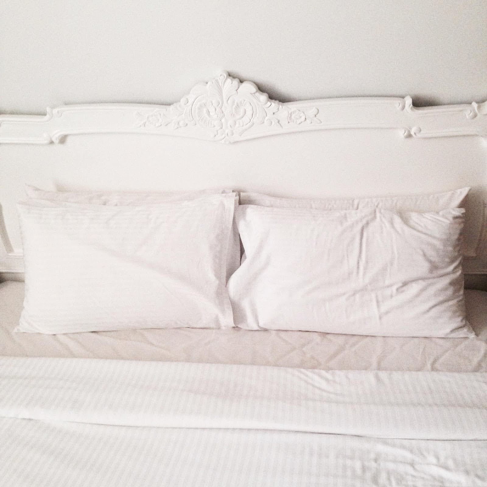 Four pillows covered in light pink pillowcases on a bed