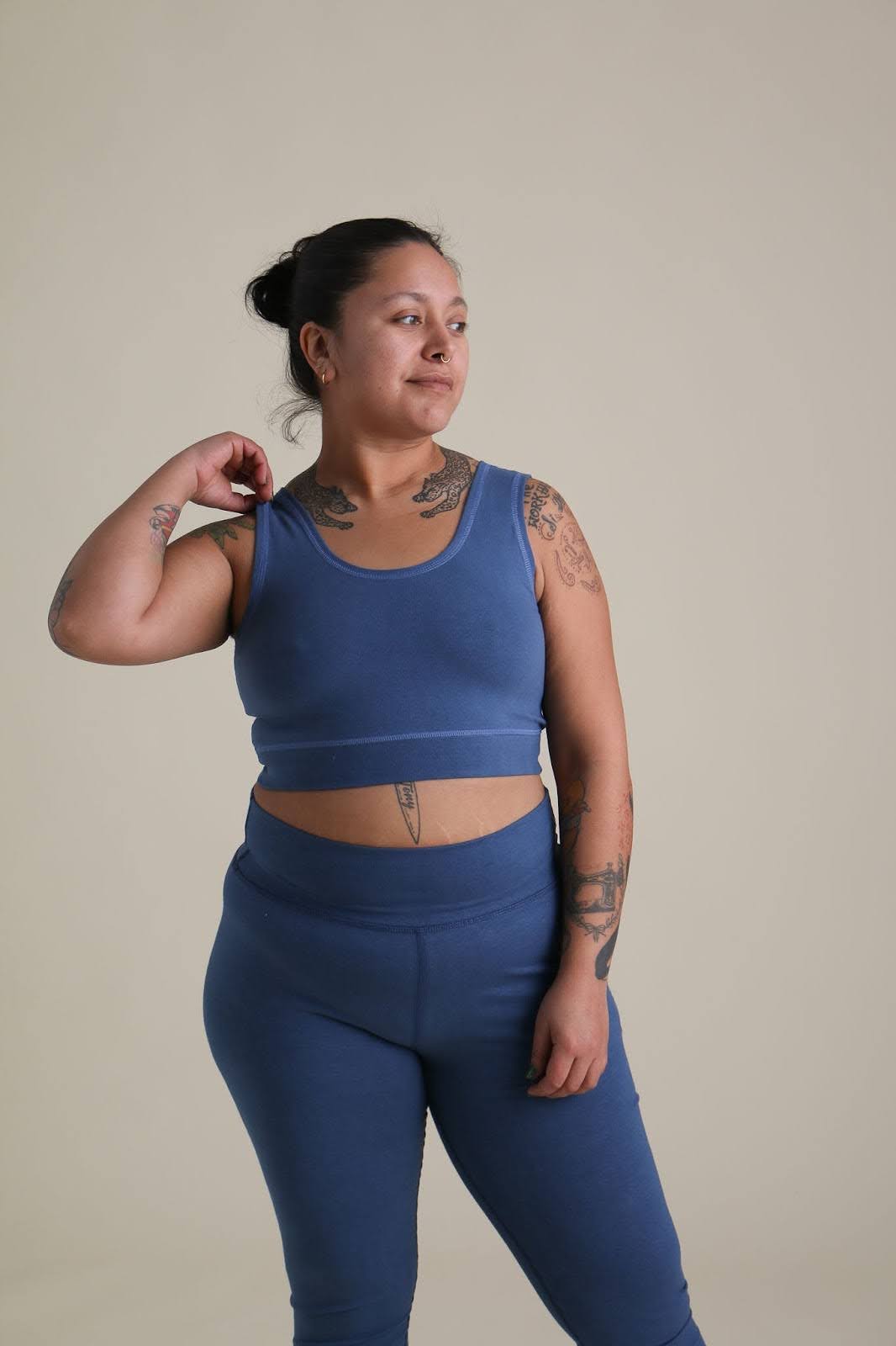 A woman with tattoos wearing a matching blue bra and leggins set