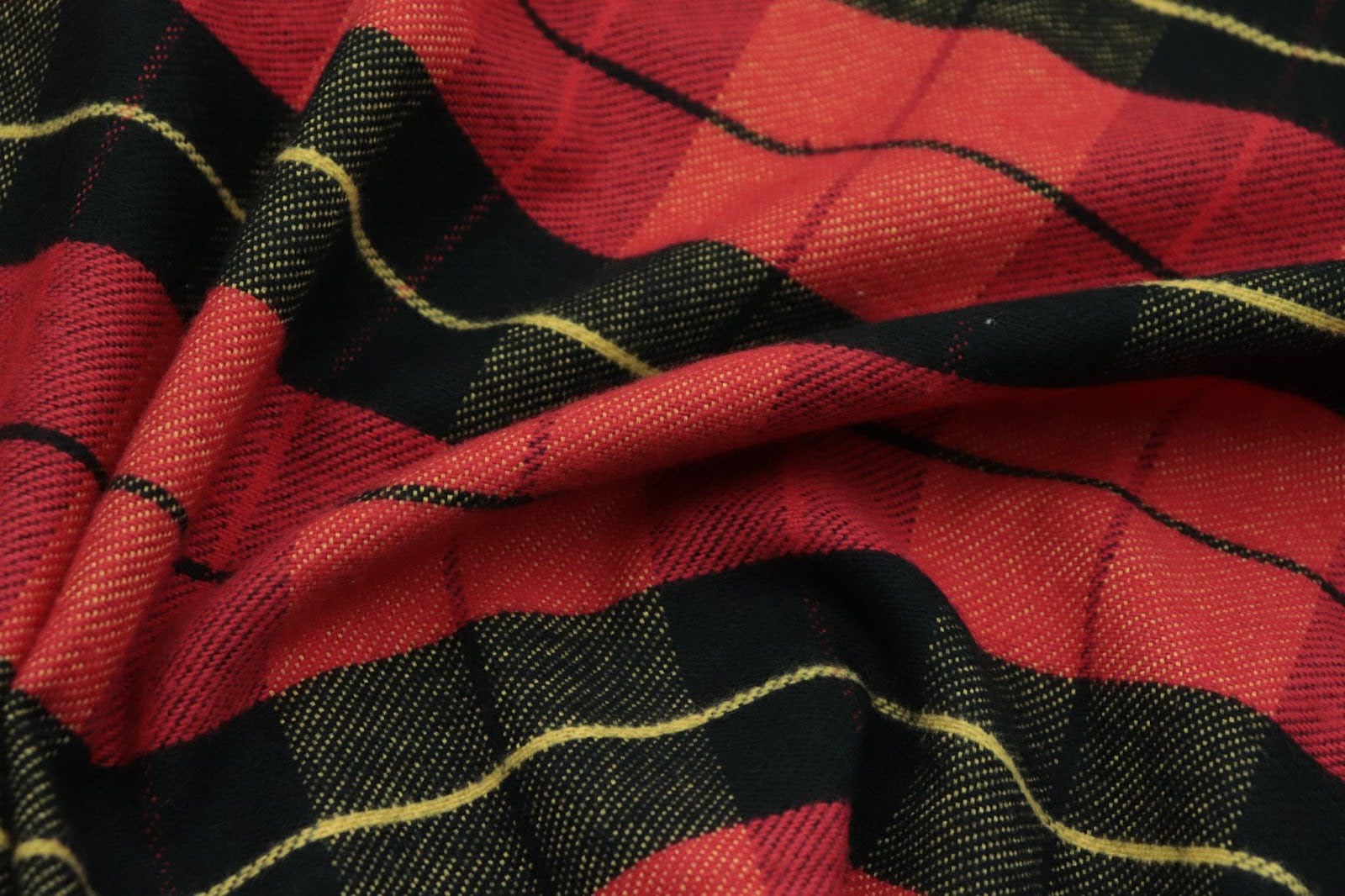 A close up of a red and black checkered blanket with yellow stripes