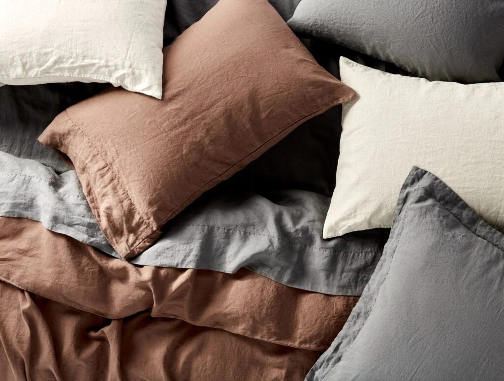 Several pillows covered in brown, cream, and gray organic linen pillowcases