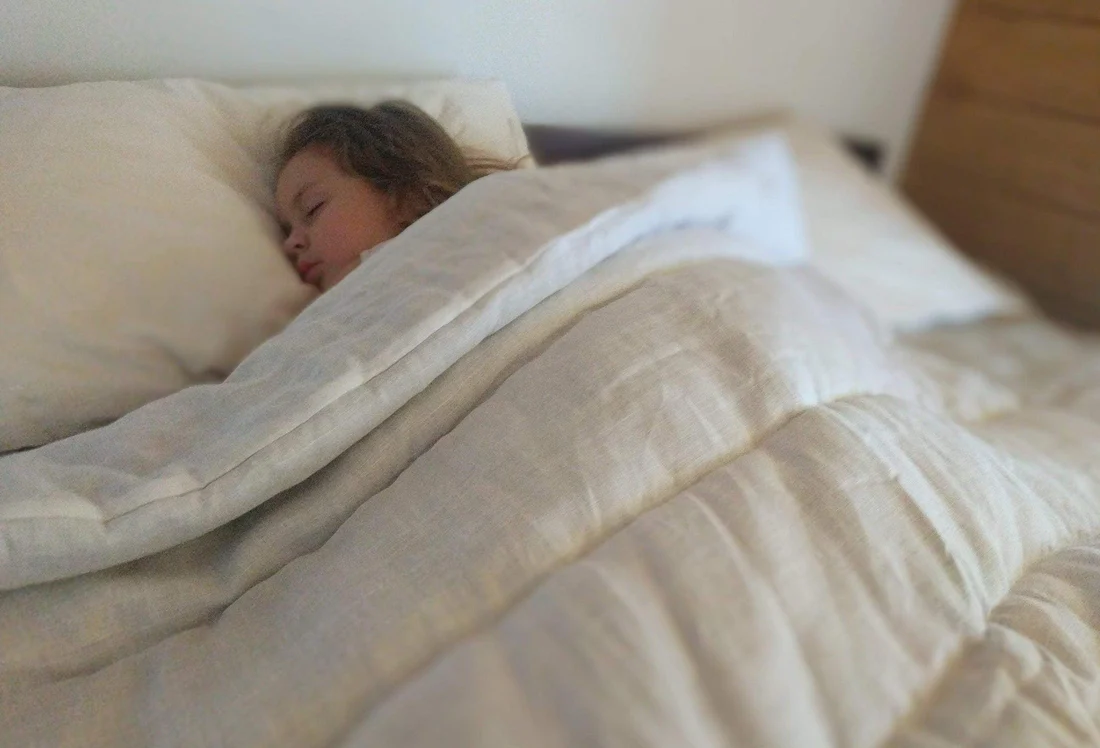 A child sleeping on a bed covered by the HempOrganicLife organic hemp comforter