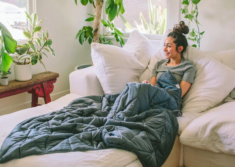 A woman lounging on the sofa with a Nest blanket