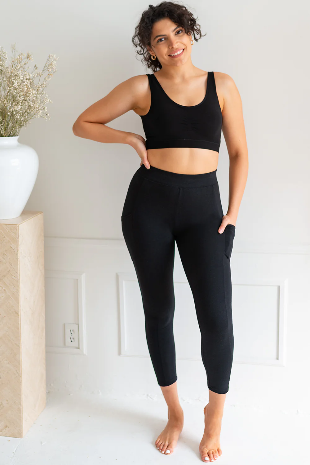 A woman wearing a black sports bra that matches her black Terrera Vida bamboo pocket leggings