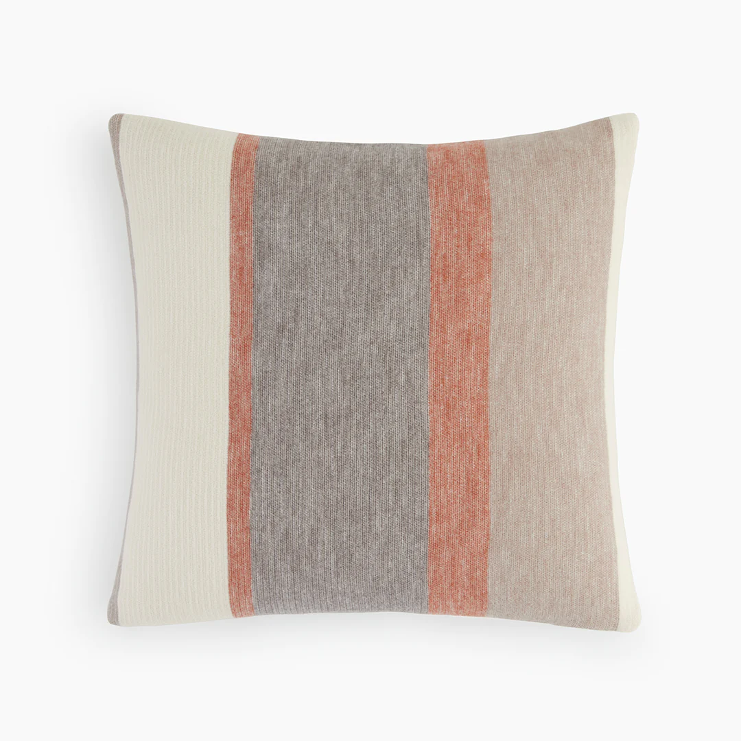 A small throw pillow covered in a striped Under the Canopy organic cotton and wool pillow cover