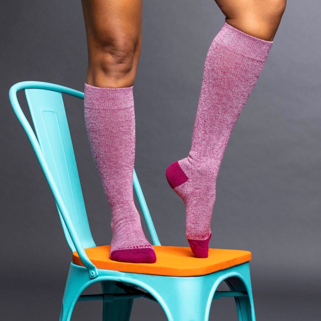 A woman standing on top of a blue and orange chair wearing bamboo compression socks