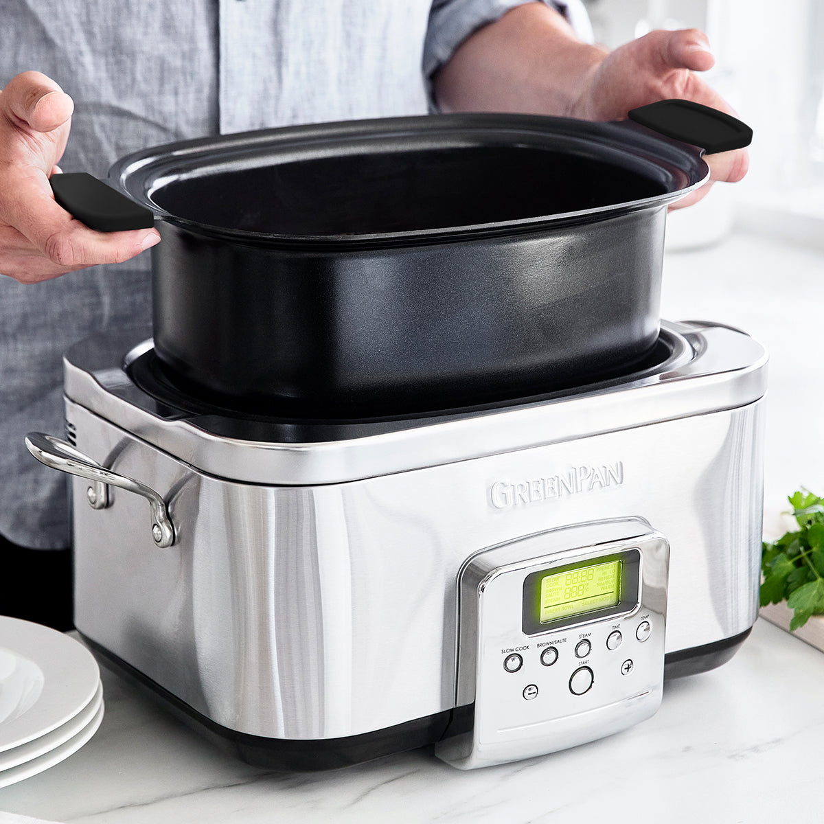 non toxic slow cooker from GreenPan, shown on a kitchen counter with someone lifting the inner compartment partially out of the cooker