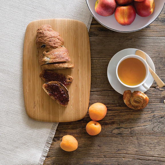 BPA-Free Cutting Board from Bambu shown with break, a pastry and various fruits 