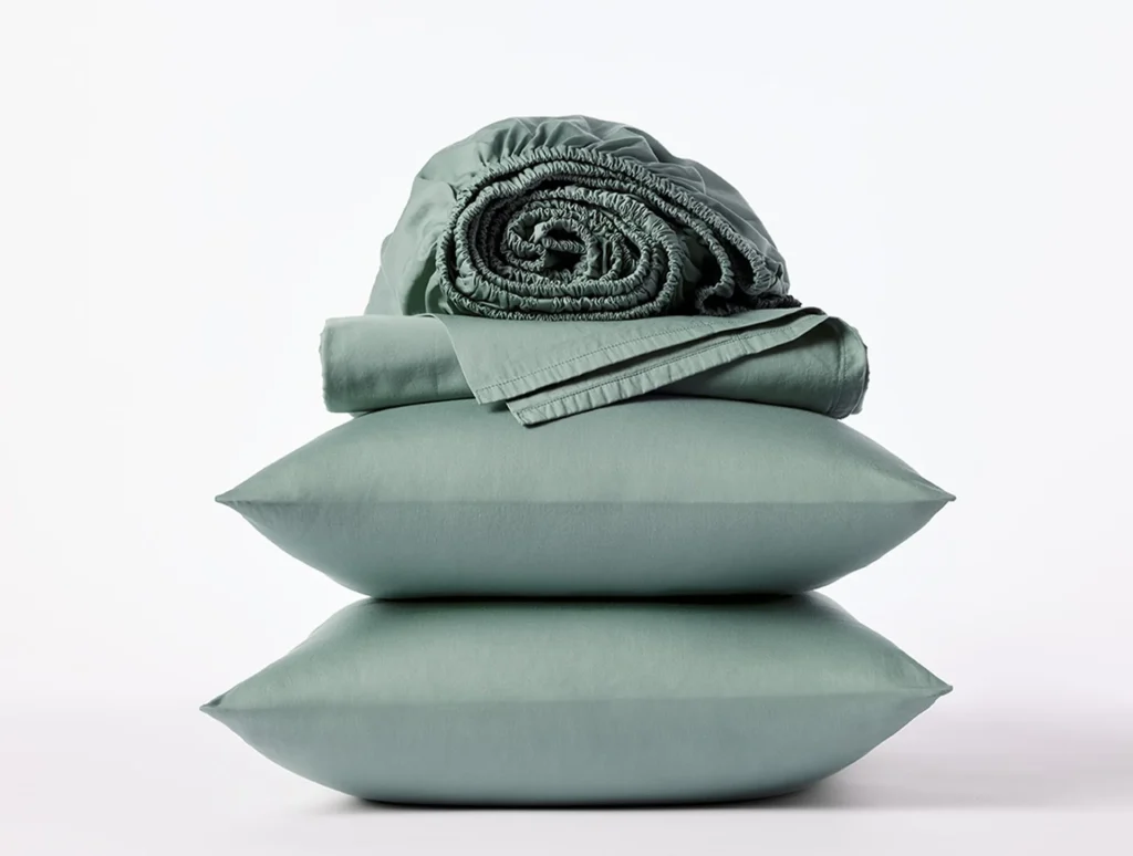 A seafoam green organic sateen sheet set from Coyuchi with two pillow covers, a flat sheet, and a fitted sheet