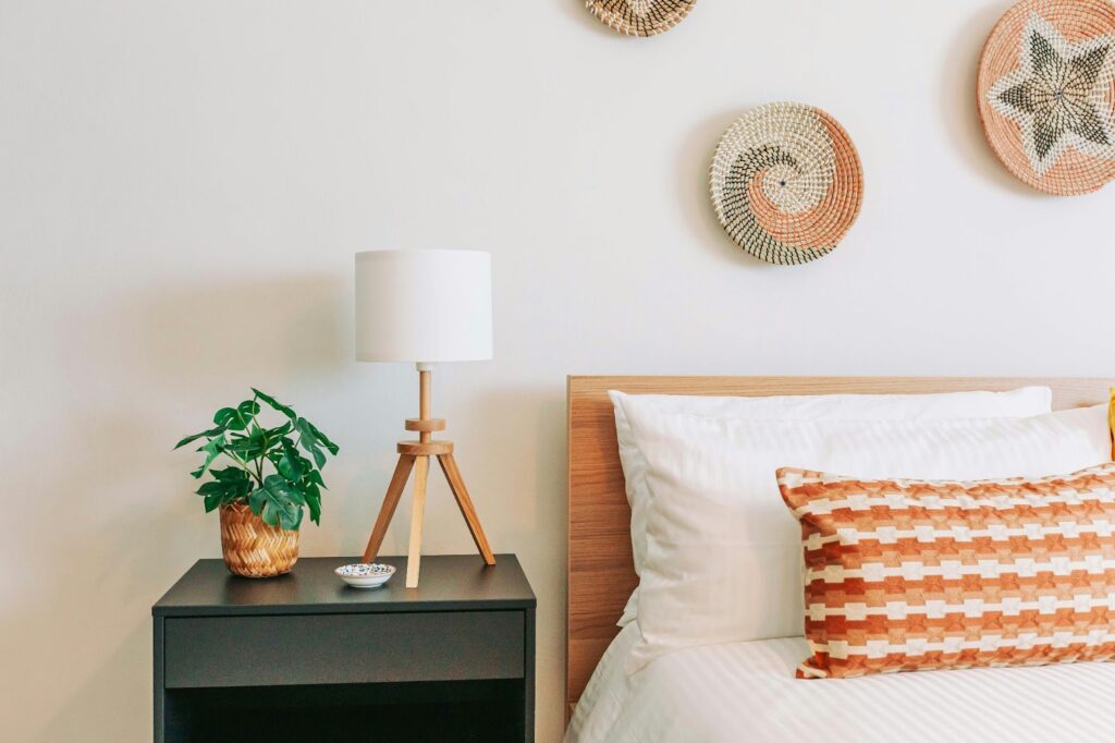 A minimalist bedroom with a bed, lamp, and plant