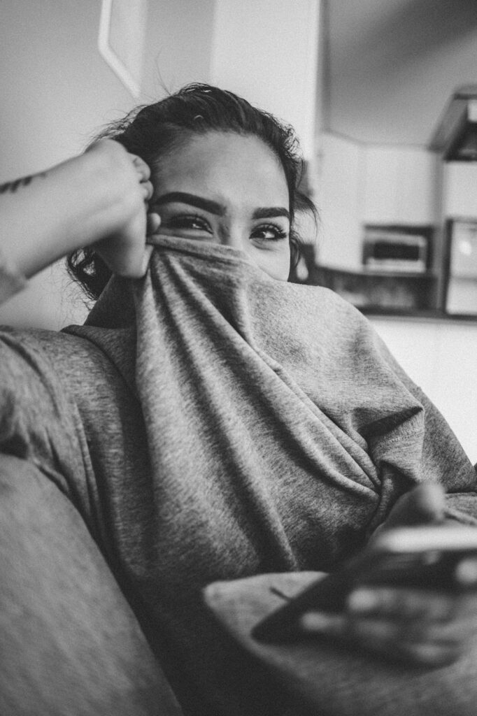 A woman covering her face with the neck of her t-shirt