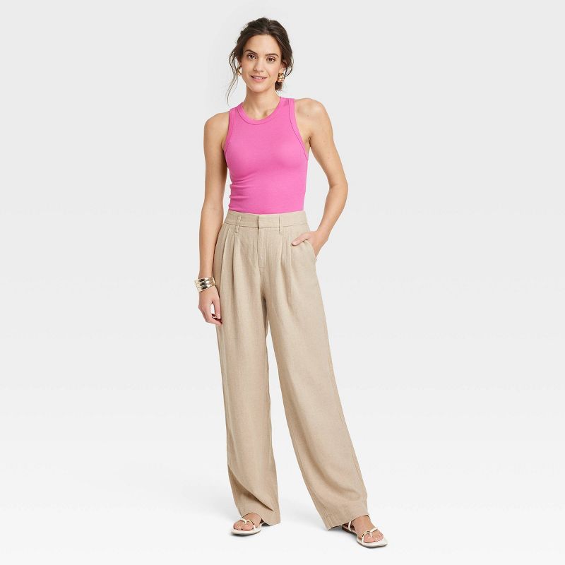 Woman wearing linen yoga pants from Target in a tan color, paired with a pink fitted tank top.