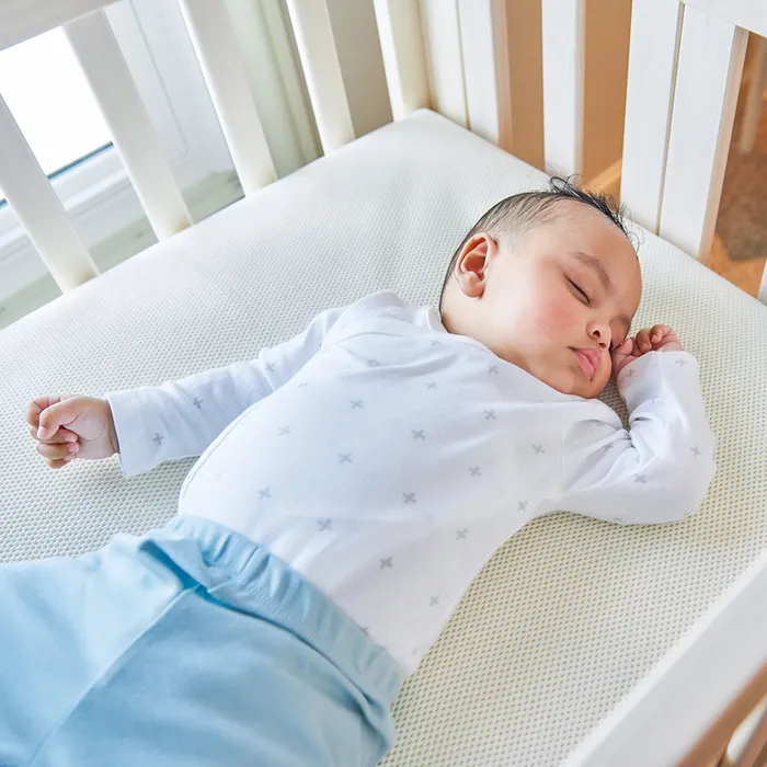A baby lays on an organic crib mattress and sleeps