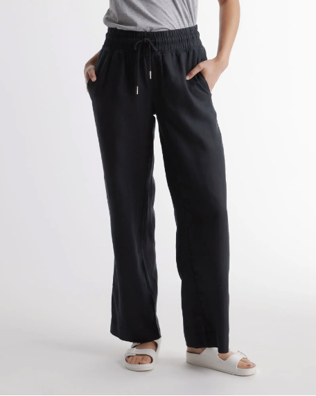 A woman wearing a gray t-shirt and a pair of black wide leg linen yoga pants from Quince