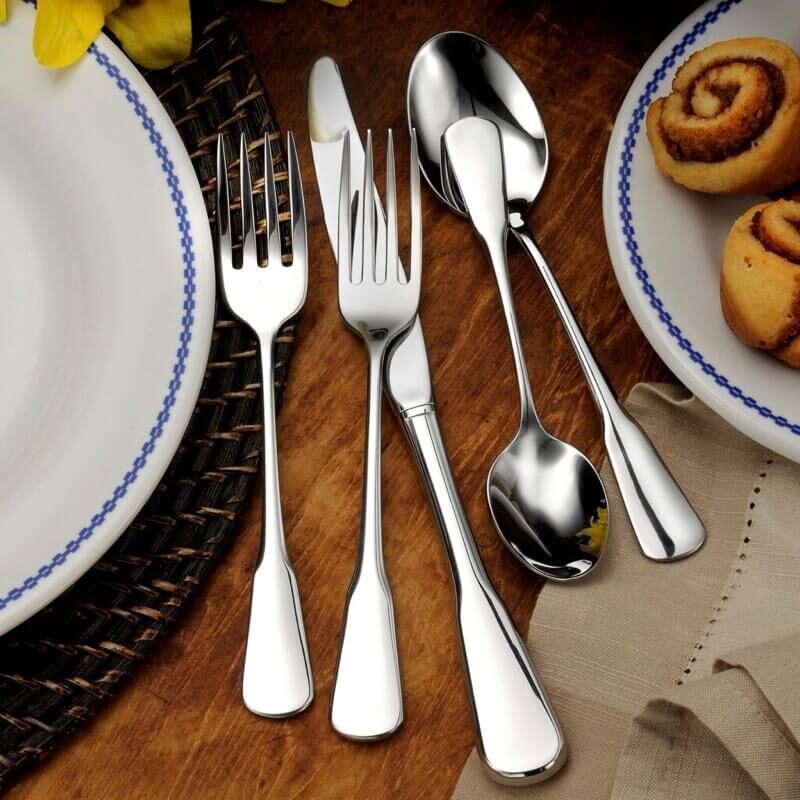 The shiny pieces of Liberty Tabletop’s Chesapeake flatware sit next to a plate of cinnamon rolls