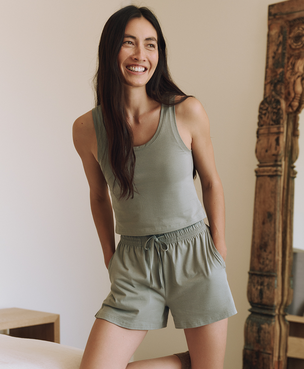 A woman wearing an olive-colored cotton pajama / loungewear set from Pact