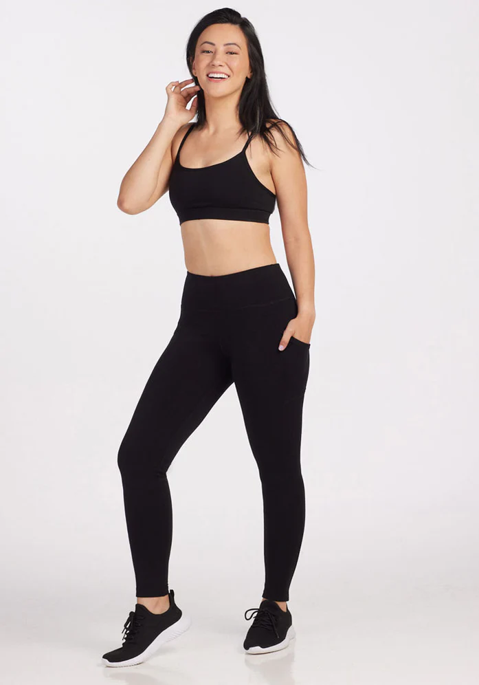 A woman wearing black sneakers, a black sports bra, and black wool leggings from Woolx