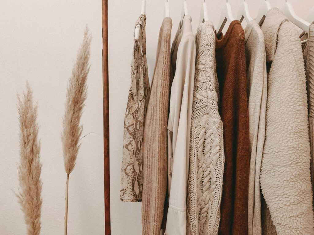 A non toxic clothing wardrobe with warm-toned clothing hanging, featuring natural fibers like linen and organic cotton.