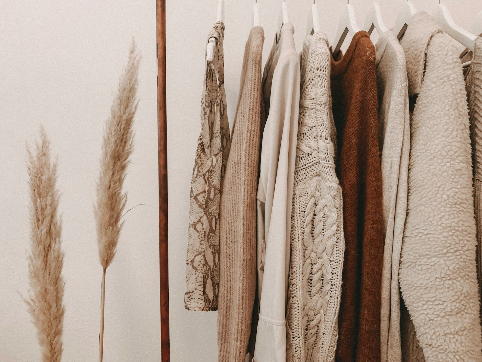 A non toxic clothing wardrobe with warm-toned clothing hanging, featuring natural fibers like linen and organic cotton.