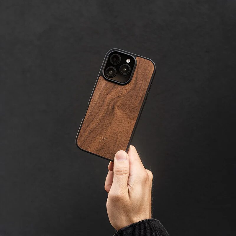 A hand holding a wooden minimalist iPhone case against a black background.