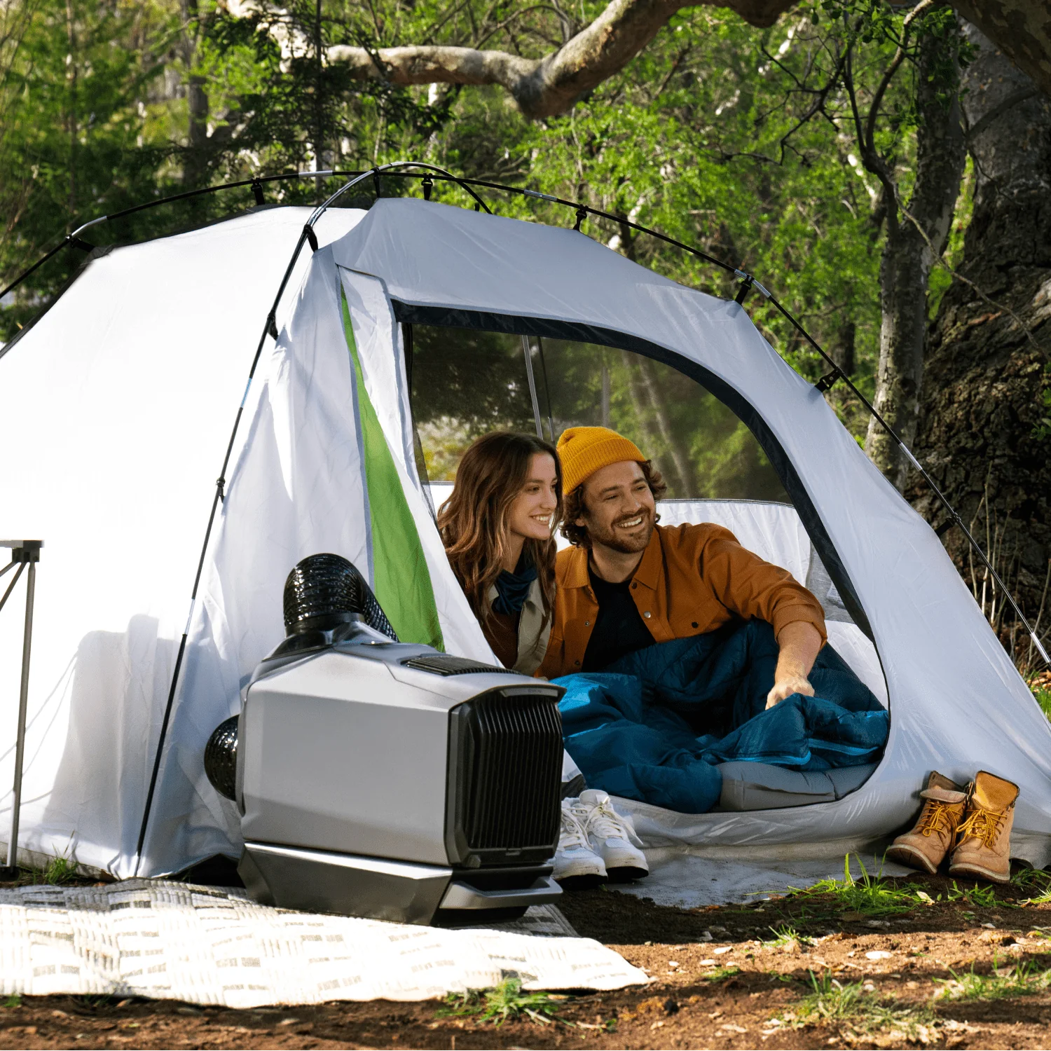 Two people smiling in a tent with a solar-powered AC unit